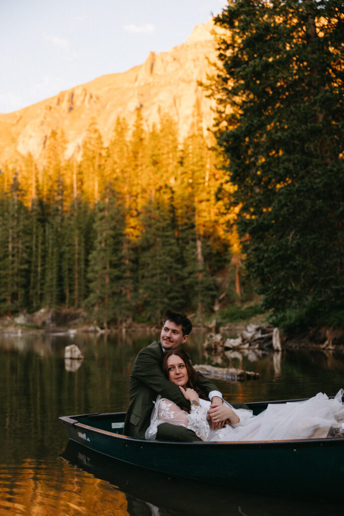 A bride and groom relax in a row boat on their wedding day during at a remote cabin in the San Juan Mountains. 