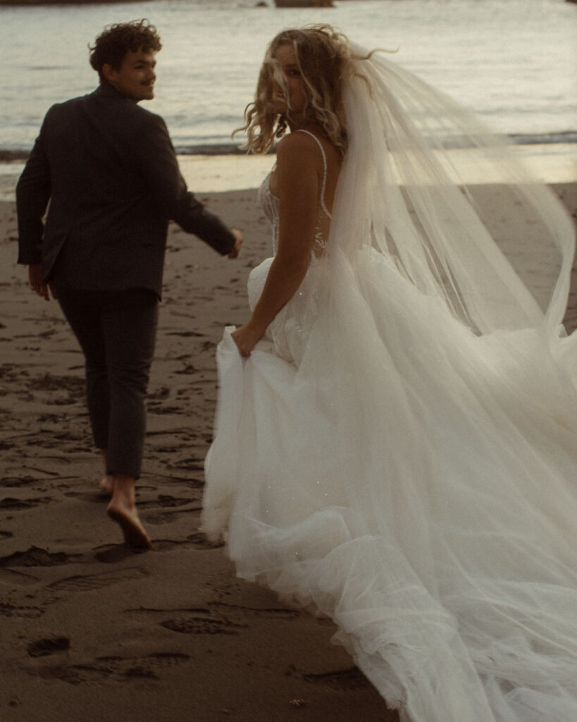 A wedding couple running towards the ocean after Eloping at Cannon Beach