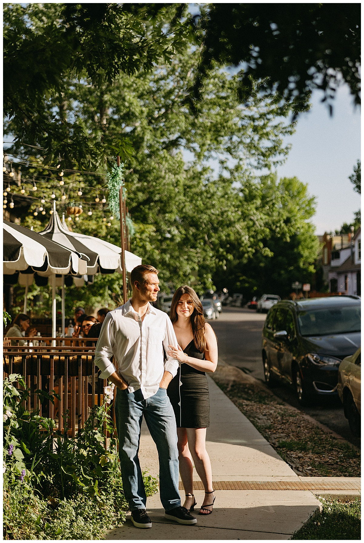 A couple stopped outside a city restaurant during their neighborhood engagement pictures.
