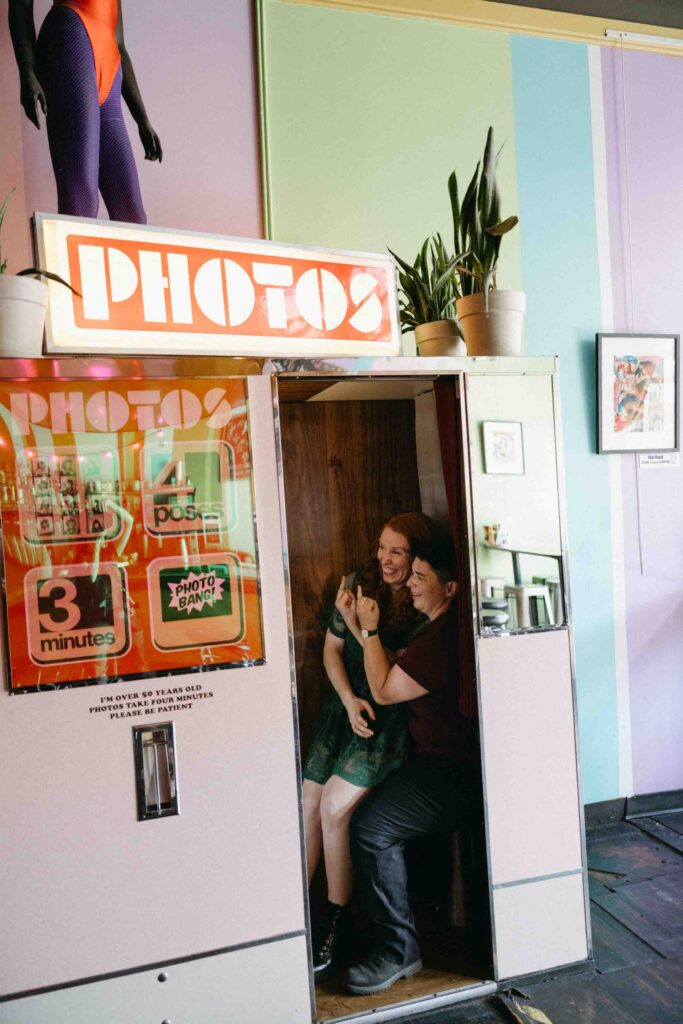 A newly engaged couple shows off their engagement rings in a photo booth at a shop in downtown Denver