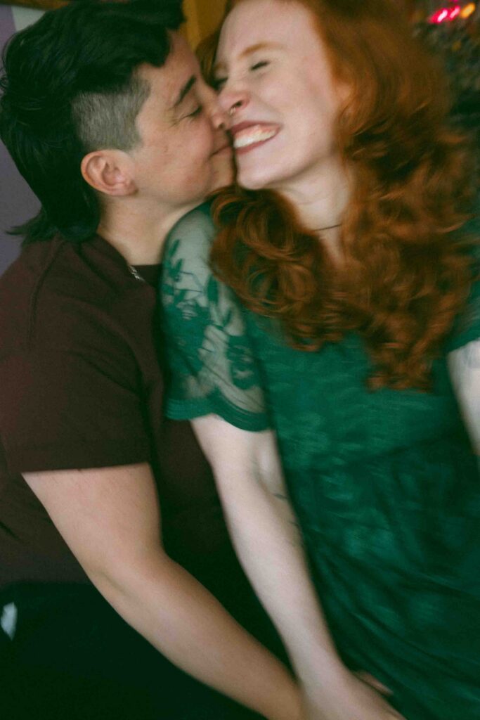 A couple kisses in a blurry candid photo during their engagement session in downtown Denver Colorado. 